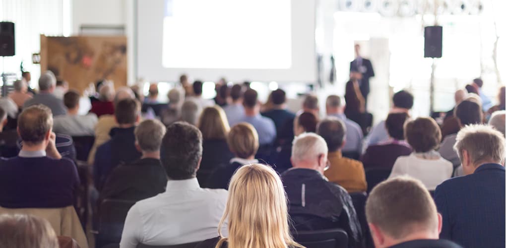 A group of people sit in chairs at an in-person lecture event