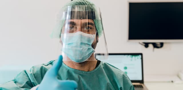 Male dentist in PPE gives a thumbs up