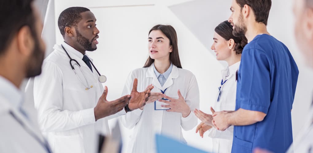 Physicians wearing white coats gather in a circle