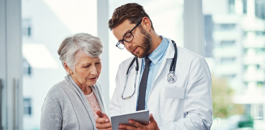 photo of doctor and patient overlooking information on a tablet