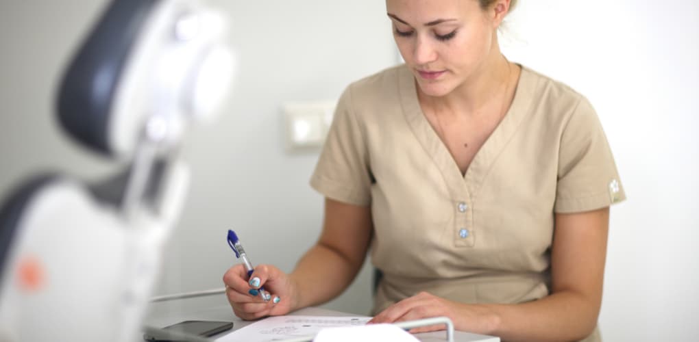 A female dentist writes a dental patient dismissal letter in the office.