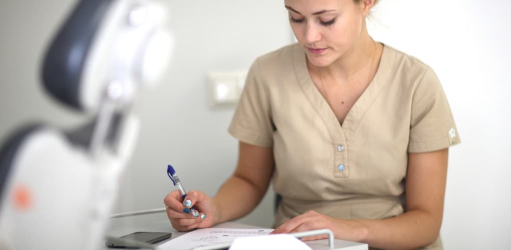 Female tech filling out paperwork in blog for disposing paper dental records