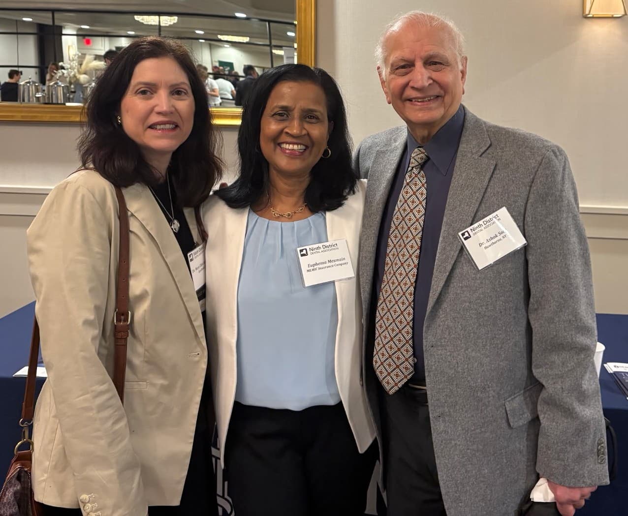three professionals smiling at an event