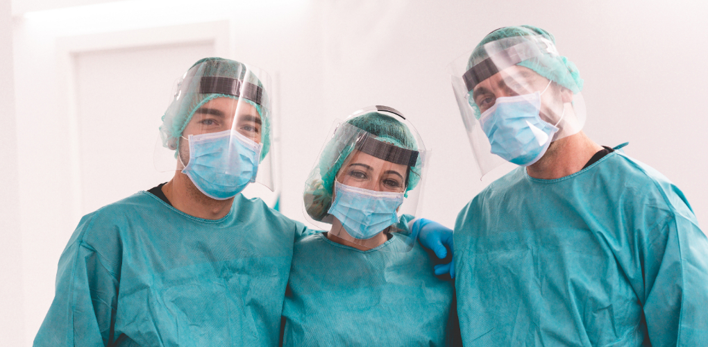 Three individuals in PPE smile and post during their dental residency.