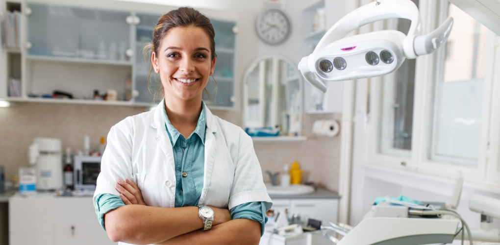 Female dentists stands alone in a dental office — blog about dentists' feeling about teledentistry