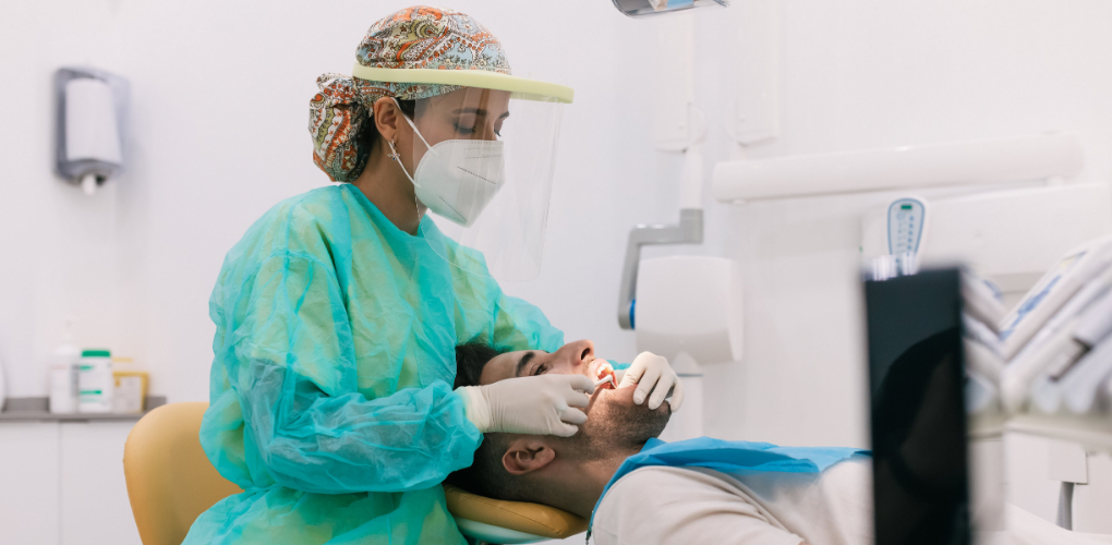 A female dentist examines the teeth of a male patient in a dental office
