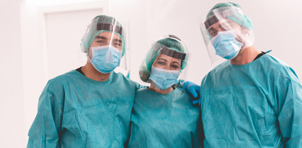 three dentists in PPE stand together smiling