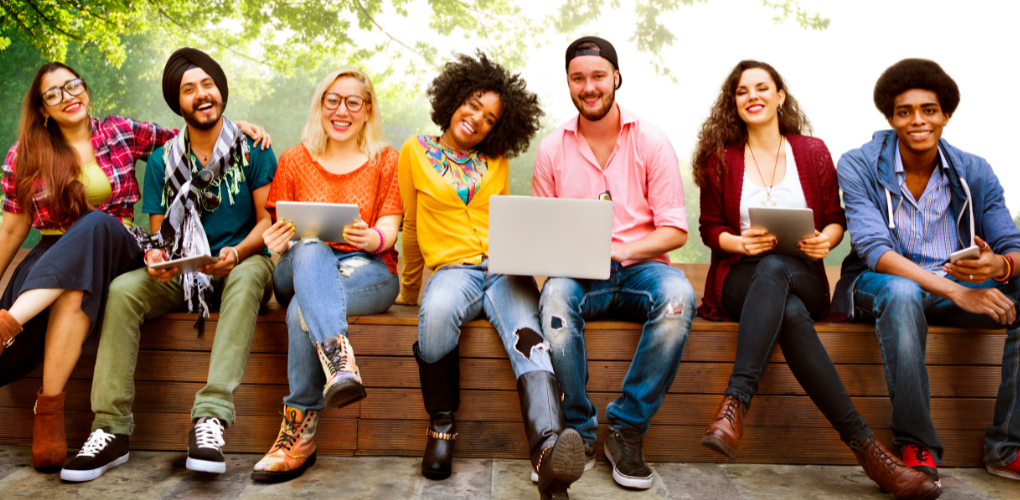 For a blog on the value of networking in dentistry, this image shows 7 young adults in colorful clothing sitting on a bench outside and smiling.