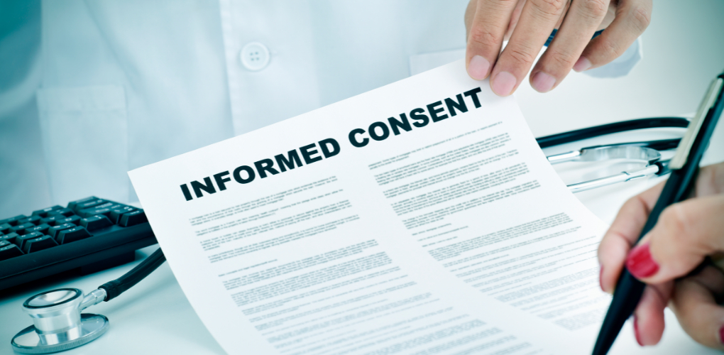 A dentist holds up a dental informed consent form for a patient to sign.