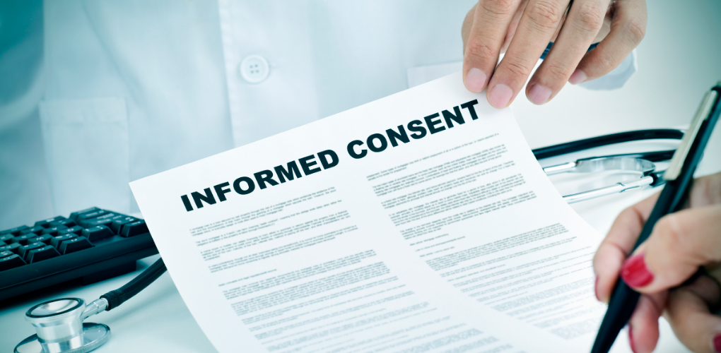 A dental patient signs an informed consent form in an office.